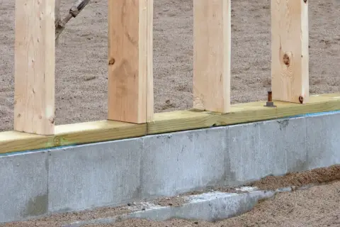 Solidny fundament pod dom szkieletowy, z drewnianymi słupkami i betonową podwaliną, gotowy na kolejne etapy budowy.