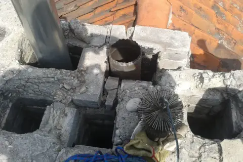 Szlamowanie komina: szczotka i rura wylotowa na dachu, gotowe do czyszczenia.